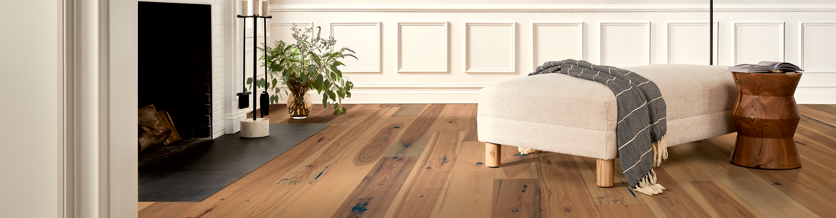 Wide plank oak hardwood floor with white ottoman, white walls 